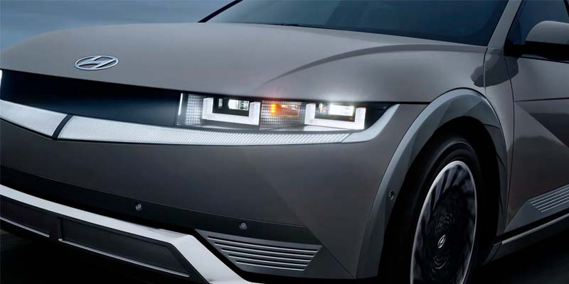 Front view of a Hyundai electric car with LED headlights on.